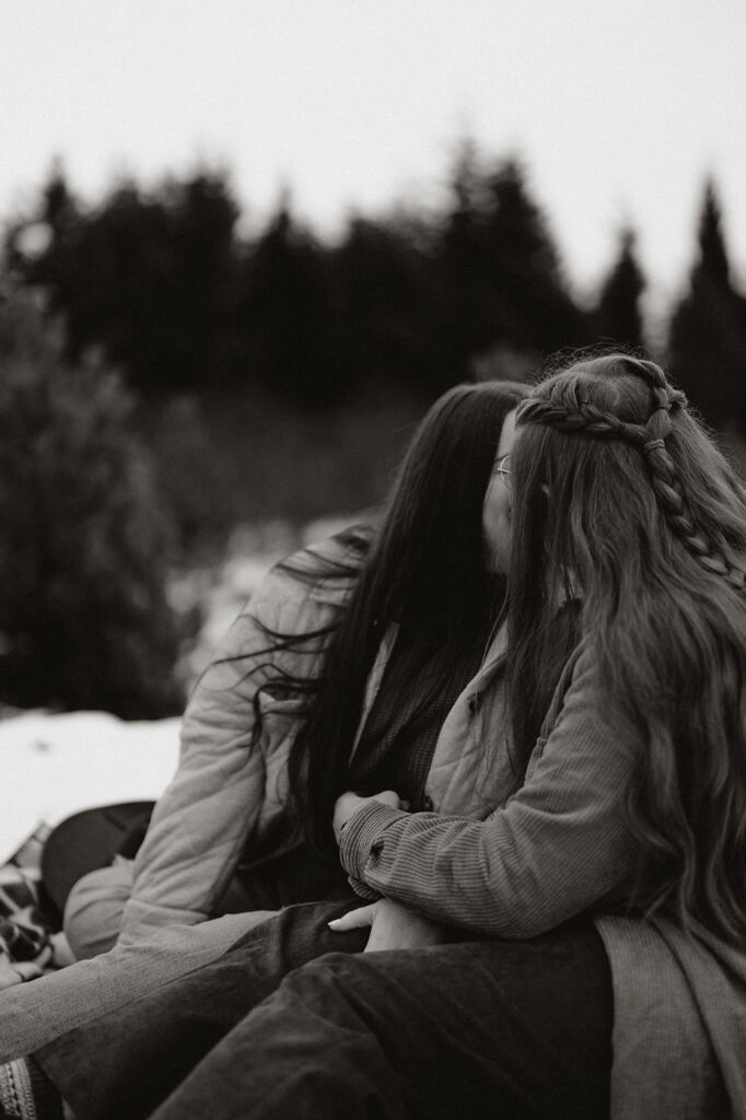 lgbtq+ couple sit on a blanket and kiss during iceland engagement photos.