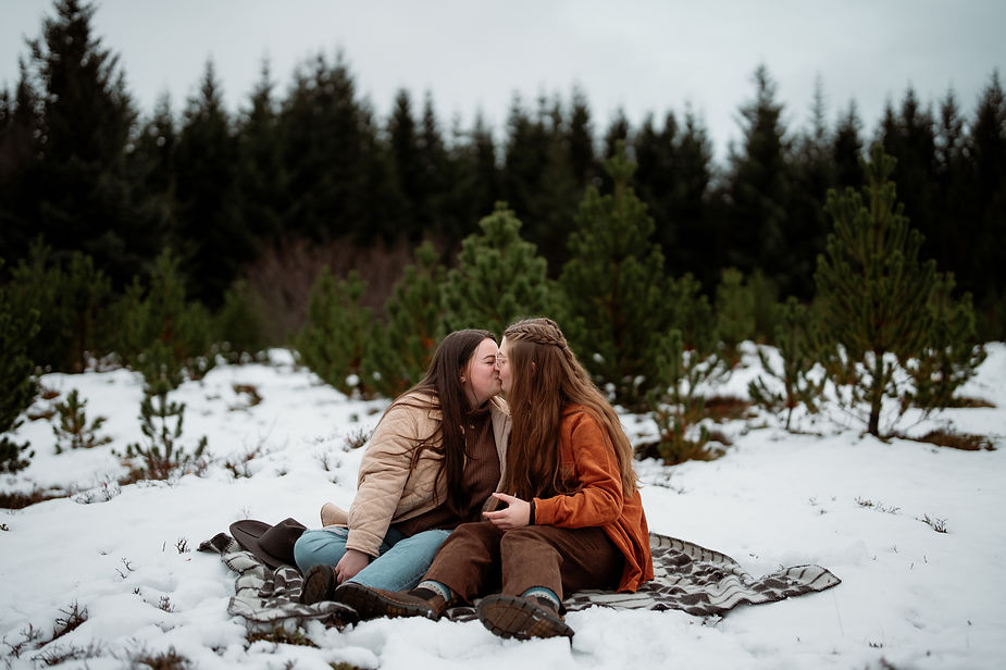 lgbtq+ couple sits on a blanket and kisses during iceland engagement pictures.