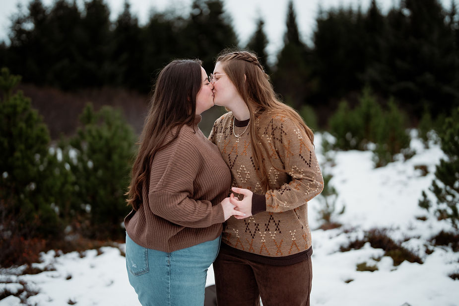 lgbtq+ couple kisses out in the snowy forest during iceland engagement photos.