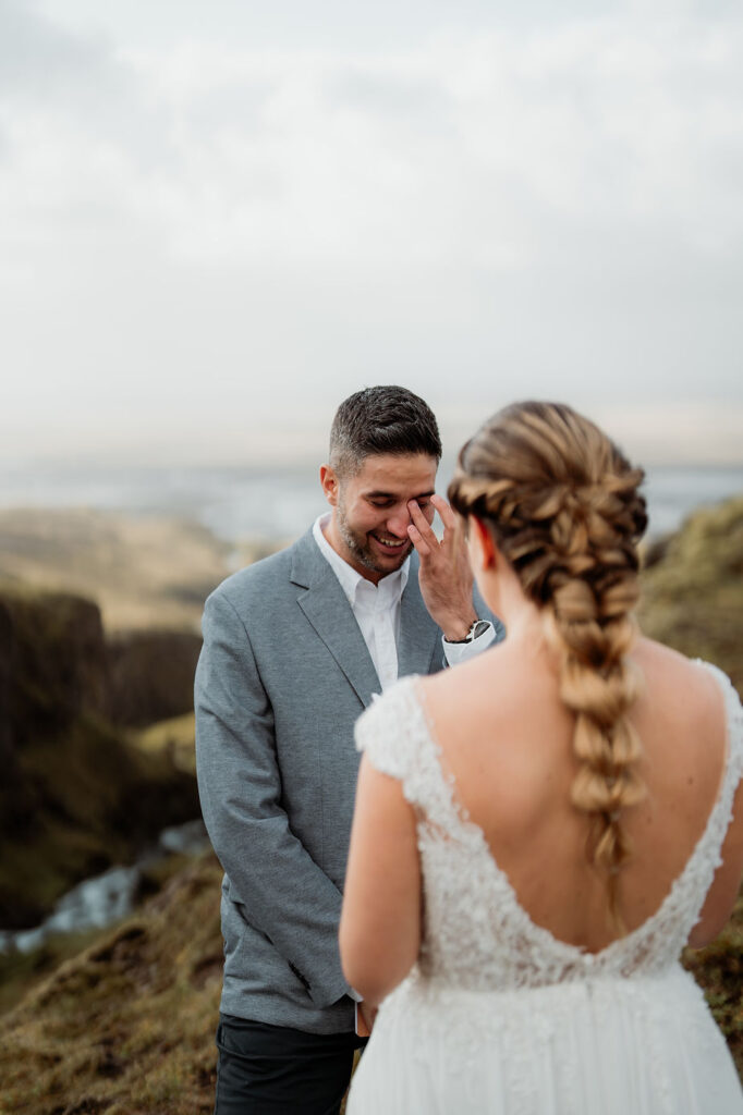 man wipes away tear during wedding first look photos.