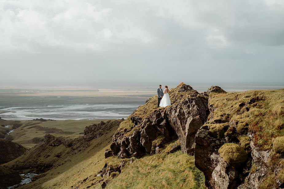 bride and groom stand on ledge and pose for iceland elopement photographer.