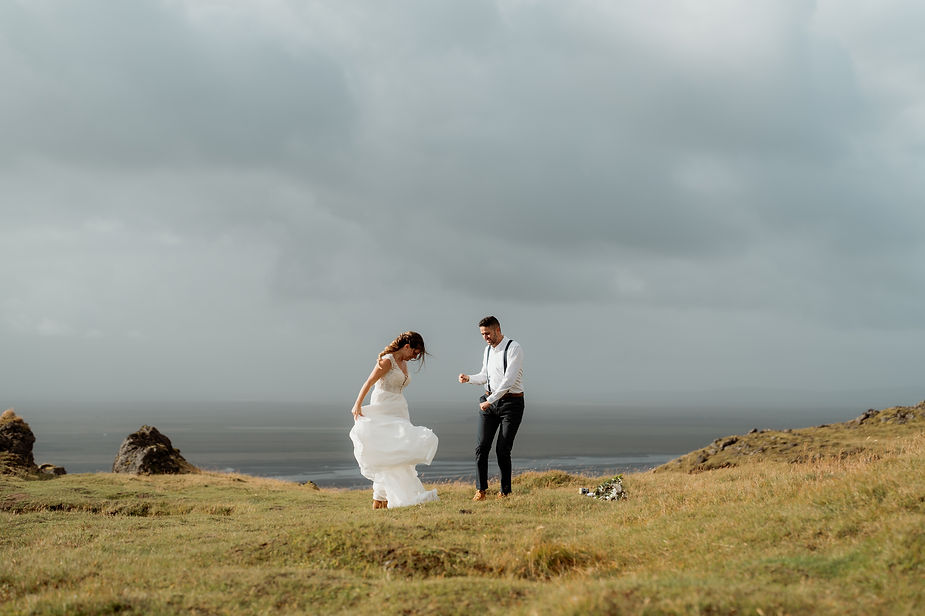 bride and groom dance on a grassy area in iceland.