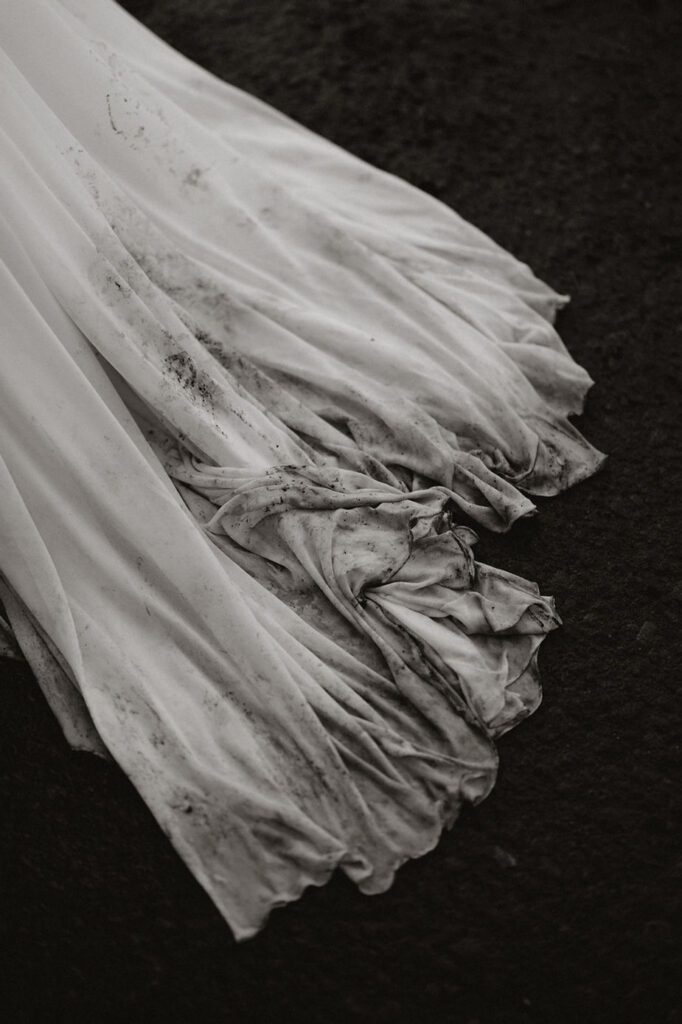 close up image of wedding dress train with black sand in it.