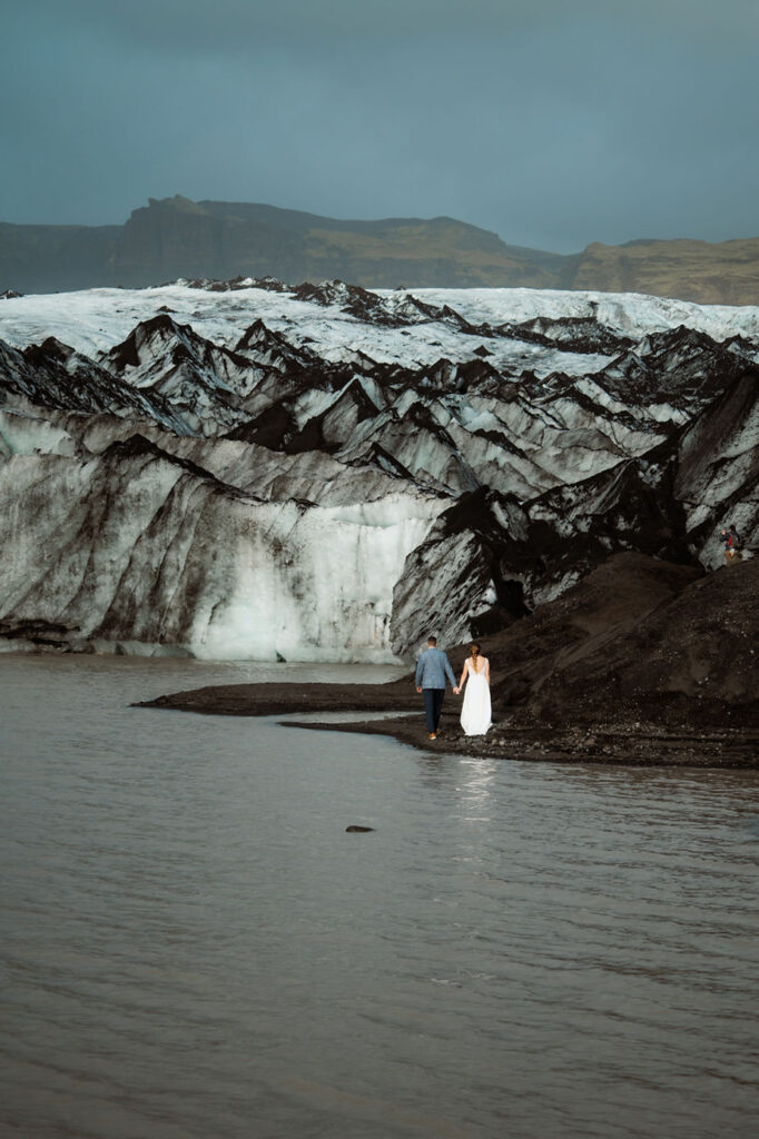 bride and groom walk beside glacier and water during their adventure elopement in iceland.