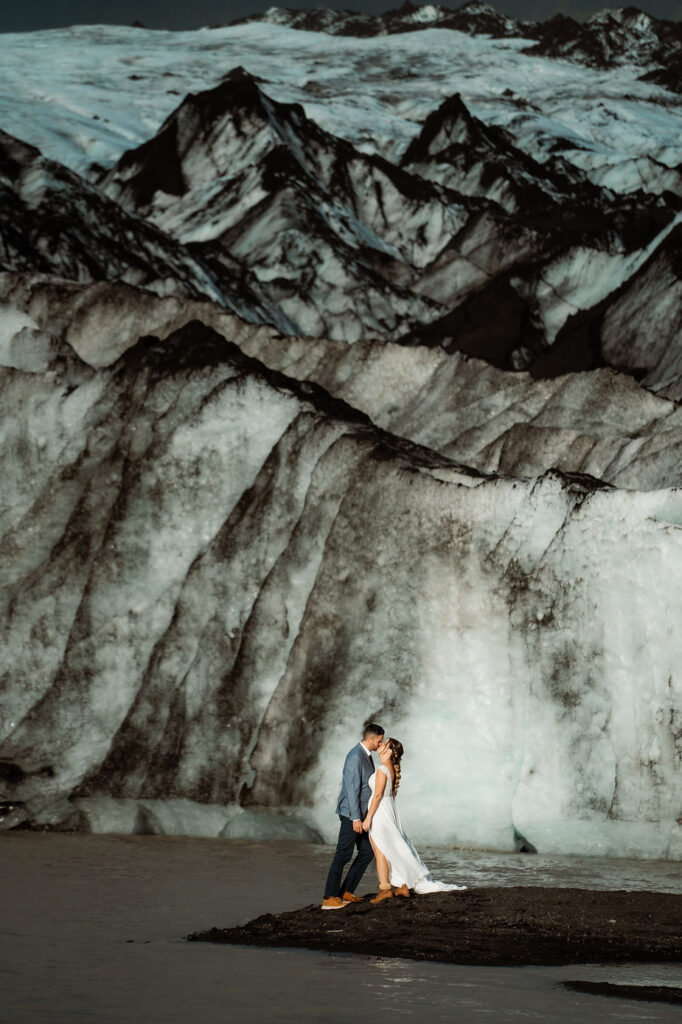 bride and groom kiss in front of glacier in iceland.