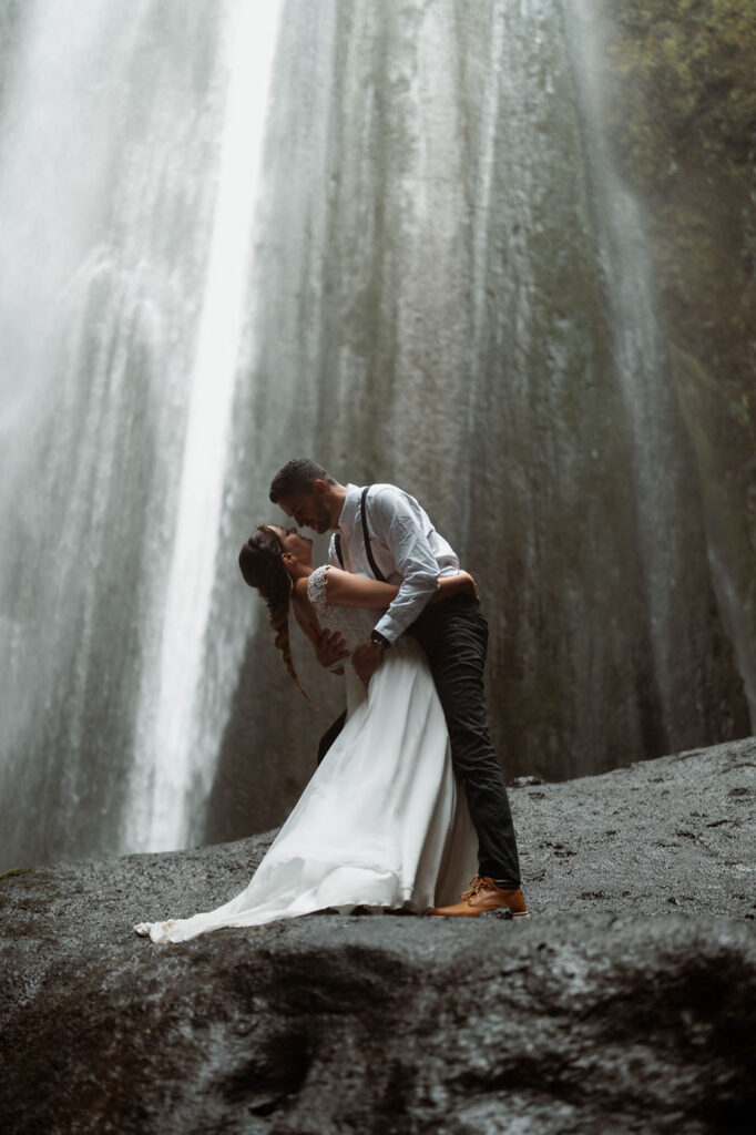 bride and groom kiss in front of waterfall in iceland during adventure elopement.
