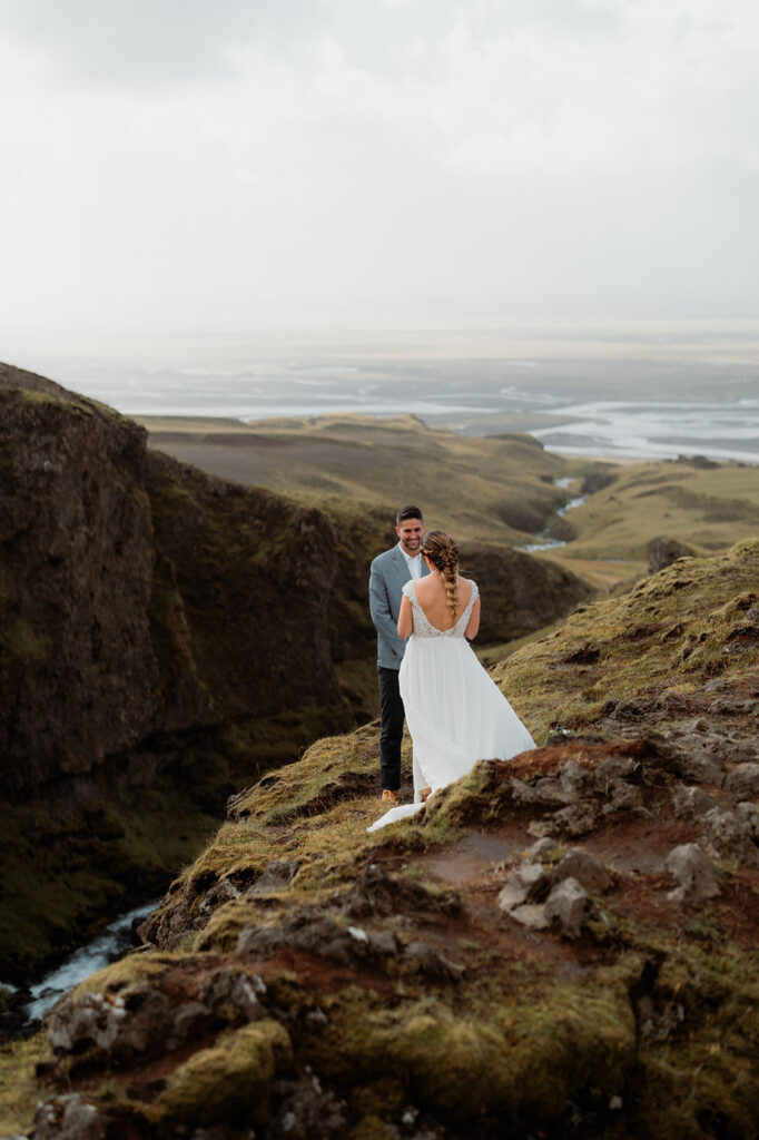 bride and groom stand over valley during adventure elopement in iceland.