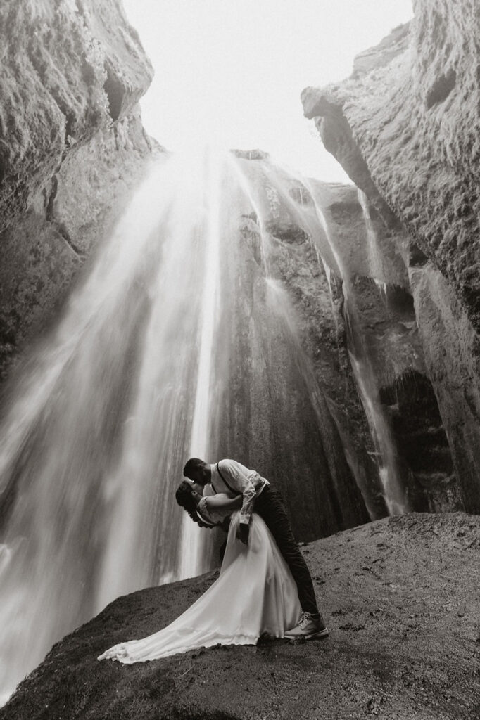 bride and groom kiss in front of waterfall during adventure elopement in iceland.