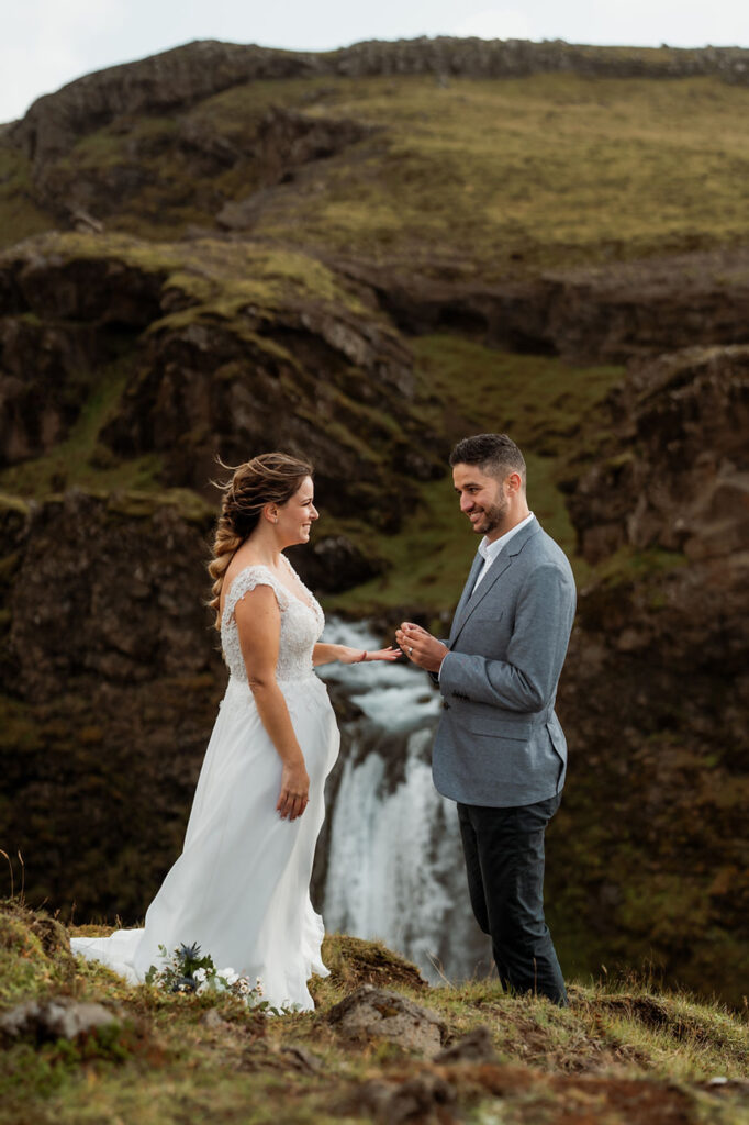 groom puts wedding ring on bride.