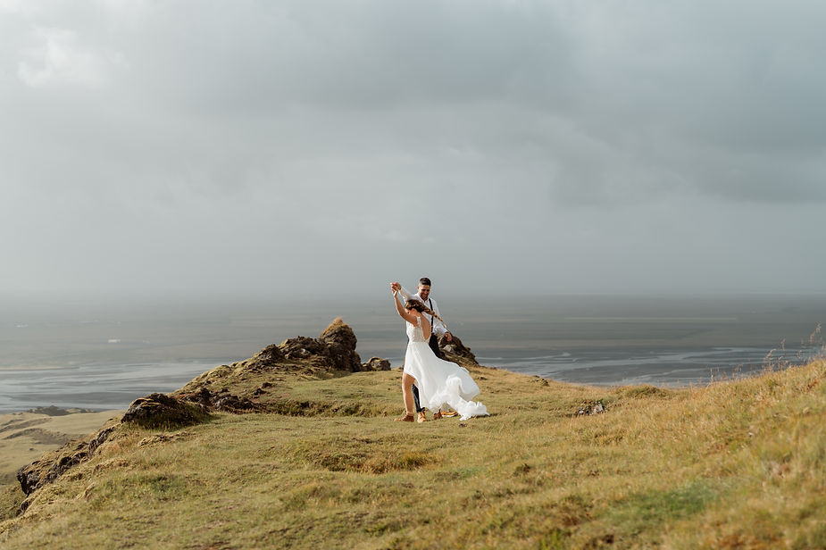 bride and groom dance on grassy area in iceland.