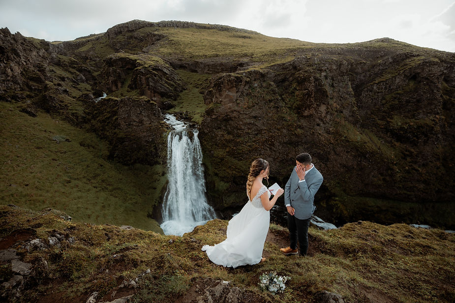 iceland wedding photographer captures bride reading vows to groom, overlooking valley in iceland.