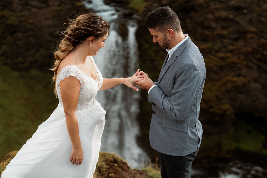 groom puts wedding ring on bride during iceland elopement.